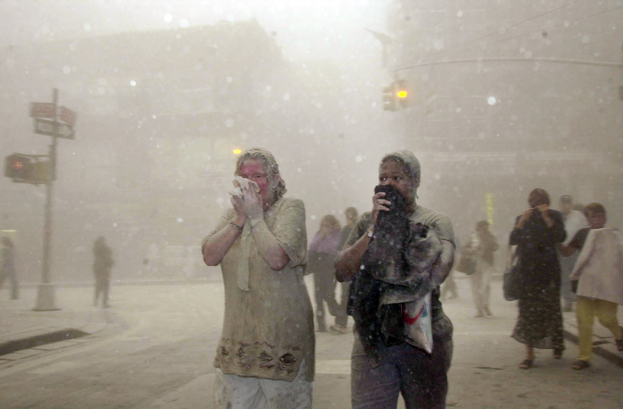 FILE -- In this Sept. 11, 2001 file photo, people covered in dust from the collapsed World Trade Center buildings, walk through the area, in New York. Two decades after the twin towers' collapse, people are still coming forward to report illnesses that might be related to the attacks.