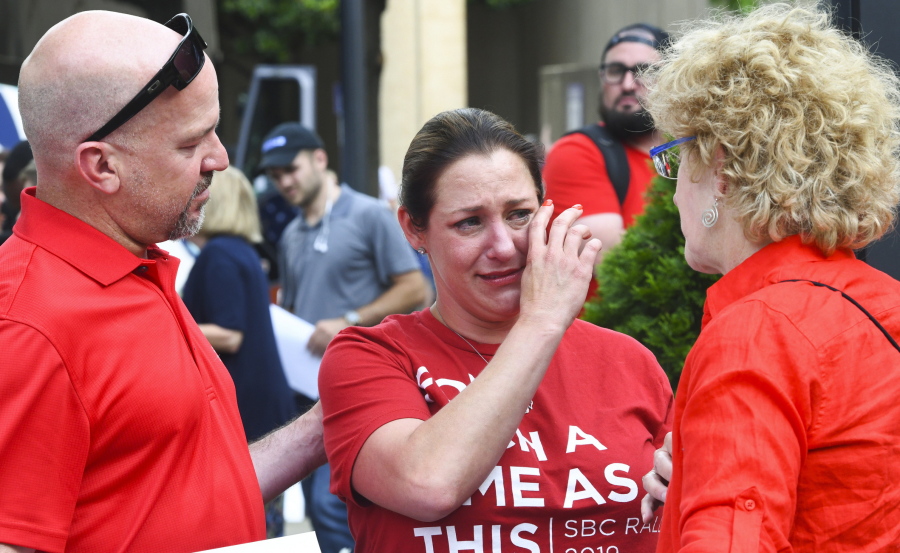 FILE - In this Tuesday, June 11, 2019 file photo, Jules Woodson, center, of Colorado Springs, Colo., is comforted by her boyfriend Ben Smith, left, and Christa Brown while demonstrating outside the Southern Baptist Convention's annual meeting in Birmingham, Ala. First-time attendee Woodson spoke through tears as she described being abused sexually by a Southern Baptist minister.