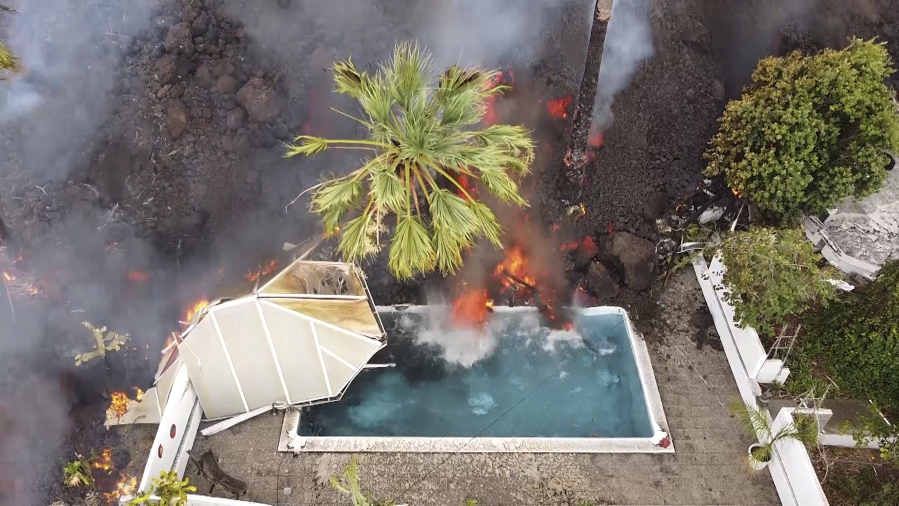 Hot lava reaches a swimming pool after an eruption of a volcano on the island of La Palma in the Canaries, Spain, Monday, Sept. 20, 2021. Giant rivers of lava are tumbling slowly but relentlessly toward the sea after a volcano erupted on a Spanish island off northwest Africa. The lava is destroying everything in its path but prompt evacuations helped avoid casualties after Sunday's eruption.
