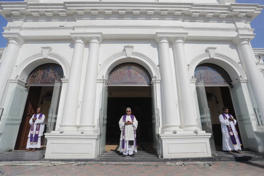 FILE- In this April 21, 2020 file photo, Sri Lankan Catholics priests stand at the entrance of St. Anthony's church, one of the sites of the 2019 Easter Sunday attacks, on the first anniversary of the deadly bombings in Colombo, Sri Lanka. A Sri Lankan Roman Catholic leader says the government must win back the confidence of the church before the two sides can hold talks on the church's criticisms of inquiries into 2019 Easter Sunday bomb blasts that killed 269 people.