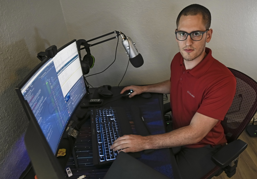 In this Sept. 20, 2021, photo Austin Moody poses for a photo as he sits a his home work station in Tampa, Fla. Moody, the Michigan native, got a scholarship from the Department of Defense that required working for the agency at least a year after graduating. Moody said he understands that state governments don't have the kind of money that federal agencies or private companies spend on recruiting and generous salaries.