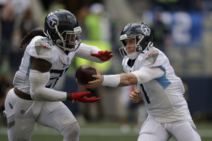 Tennessee Titans quarterback Ryan Tannehill, right, hands off to running back Derrick Henry during the second half of an NFL football game against the Seattle Seahawks, Sunday, Sept. 19, 2021, in Seattle. The Titans won 33-30 in overtime.