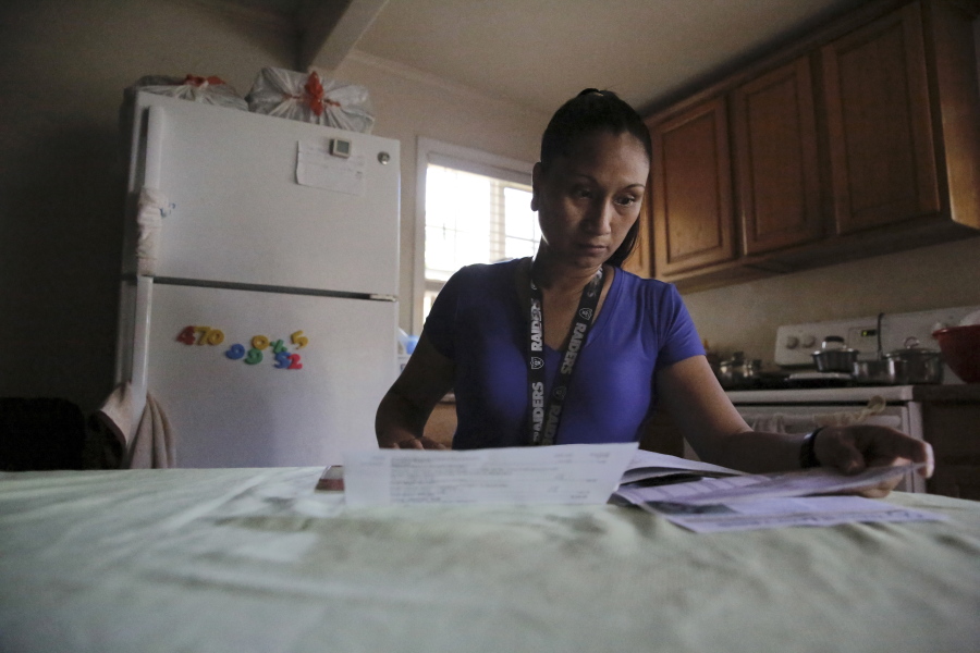 Mary Taboniar, a housekeeper at the Hilton Hawaiian Village resort in Honolulu, looks over bills at her home in Waipahu, Hawaii, Saturday, Sept. 4, 2021. Taboniar went 15 months without a paycheck, thanks to the COVID pandemic. The single mother of two saw her income completely vanish as the virus devastated the hospitality industry. Taboniar is one of millions of Americans for whom Labor Day 2021 represents a perilous crossroads.