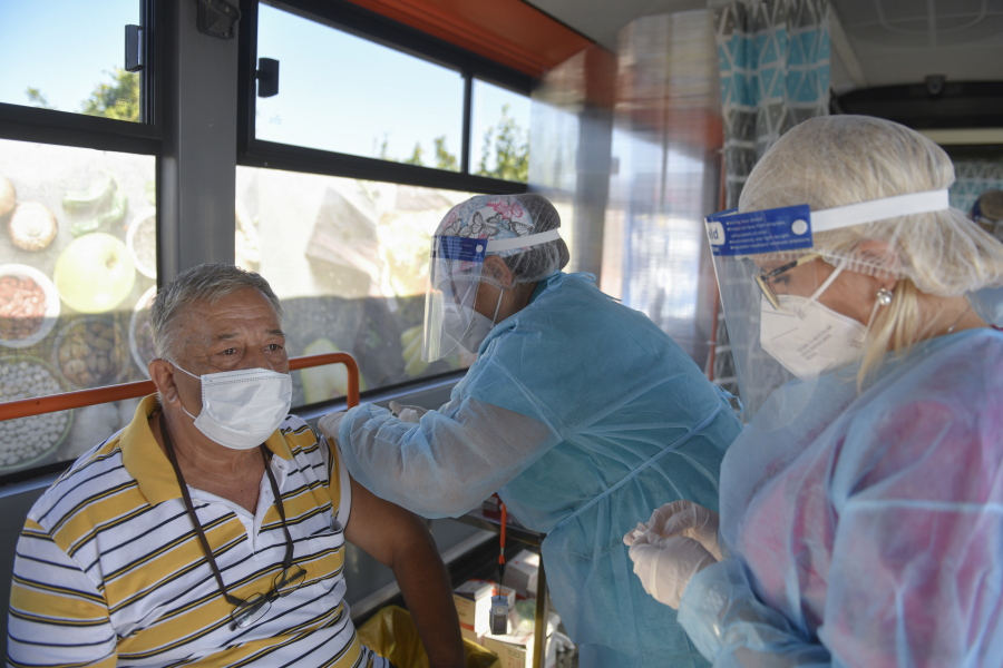FILE - In this Sept. 4, 2021, file photo, a man receives the Johnson & Johnson vaccine in a bus that serves as a mobile COVID-19 vaccination unit in Bucharest, Romania. In both the U.S. and the EU, officials are struggling with the same question: how to boost vaccination rates to the max and end a pandemic that has repeatedly thwarted efforts to control it. In the European Union, officials in many places are requiring people to show proof of vaccination, a negative test or recent recovery from COVID-19 to participate in everyday activities -- even sometimes to go to work.