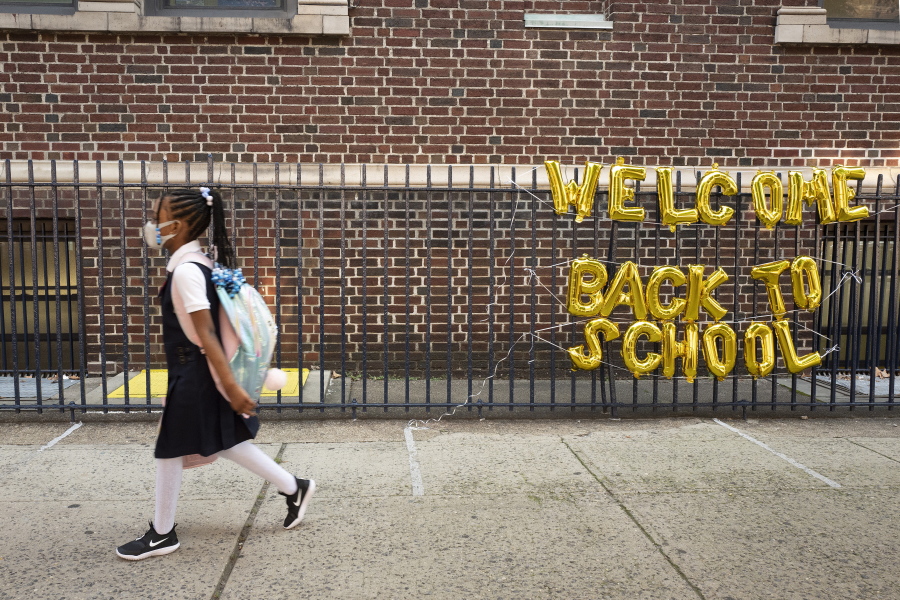 FILE - In this Sept. 13, 2021, file photo, a girl passes a "Welcome Back to School" sign as she arrives for the first day of class at Brooklyn's PS 245 elementary school in New York.