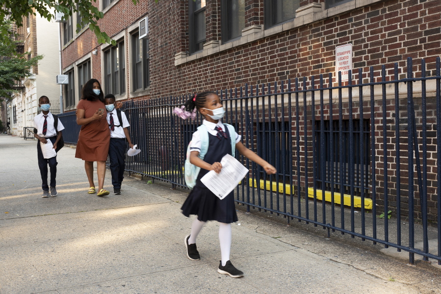 A girl leads her mother and brothers as they arrive at Brooklyn's PS 245, Monday, Sept. 13, 2021, in New York. Classroom doors are swinging open for about a million New York City public school students in the nation's largest experiment of in-person learning during the coronavirus pandemic.