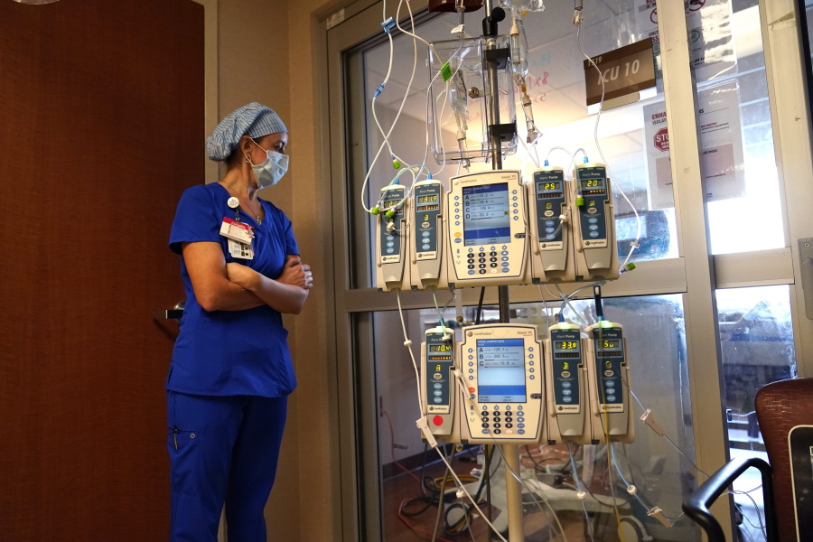 FILE - In this Aug. 17, 2021, file photo, nursing coordinator Beth Springer looks into a patient's room in a COVID-19 ward at the Willis-Knighton Medical Center in Shreveport, La. COVID-19 deaths in the U.S. have climbed to an average of more than 1,900 a day for the first time since early March, with experts saying the virus is preying largely on a select group: 71 million unvaccinated Americans.