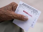 A man holds his vaccination reminder card after having received his first shot at a pop-up vaccination site.