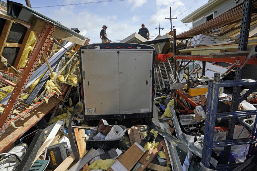 FILE - In this Monday, Aug. 30, 2021, file photo, Jacob Hodges, right, and his brother Jeremy Hodges work to clear debris from their storage unit which was destroyed by Hurricane Ida, in Houma, La. A new report from the United Nations weather agency finds the world is getting several times more weather disasters than in the 1970s. (AP Photo/David J.
