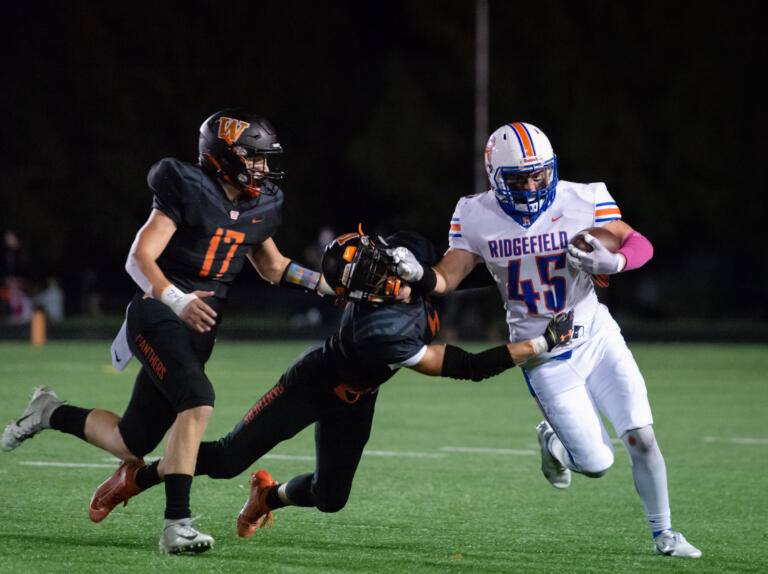 Ridgefield's Connor Delamarter stiff arms a Washougal defender in a 2A Greater St. Helens League football game on Friday, Oct. 1, 2021, at Fishback Stadium in Washougal.