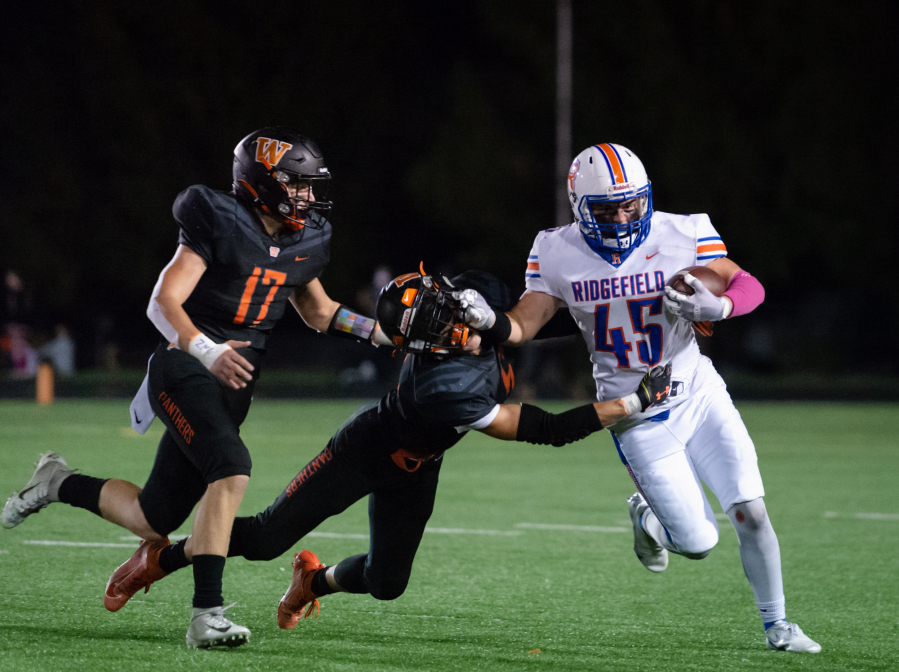 Ridgefield's Connor Delamarter stiff arms a Washougal defender during Friday's 2A Greater St. Helens League game.