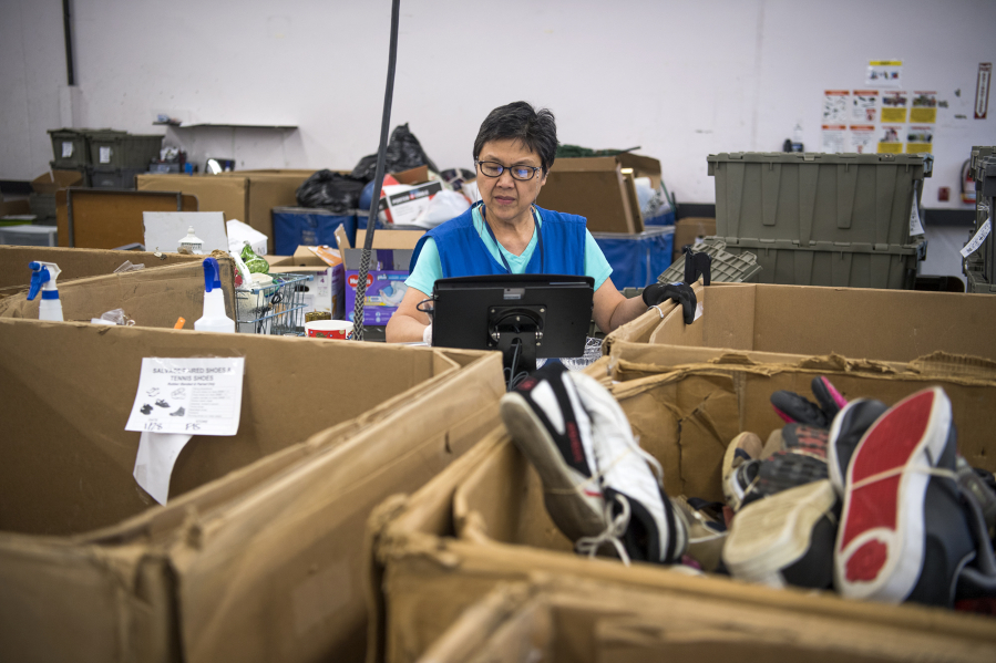 Lucia Mercado of Washougal sorts items in the intake area of Goodwill in Vancouver on Friday, Feb. 1, 2018.