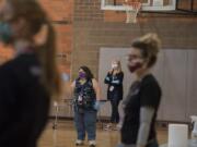 Paraeducator Darcy Wells, in a purple mask, greets a parent as they enter the gym to pick up an iPad for a child at Washington Elementary School at the onset of the pandemic in early 20202.
