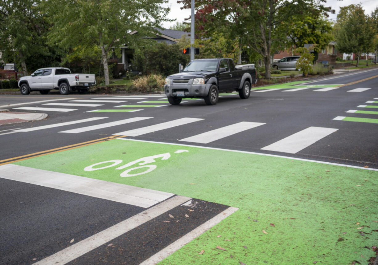 A truck drives through the intersection of Columbia and 33rd Street, which has been transformed with green-painted bike boxes showing safe areas for cyclists as part of the city's Westside Bike Mobility Project.