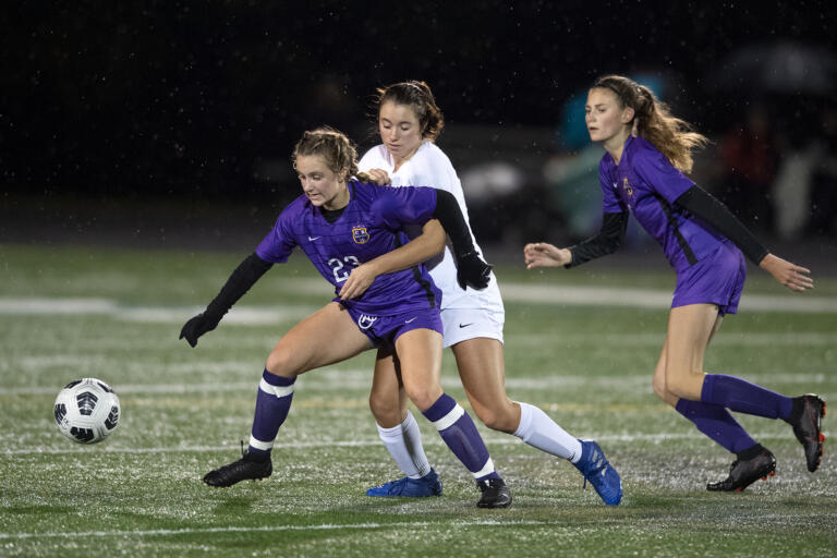 Columbia River's Sydney Johnson (23) battles Ridgefield's Kelli Krsul (16) for the ball as teammate Logann Dukes (15) looks on In the first half at Columbia River High School on Tuesday night, Oct. 12, 2021.