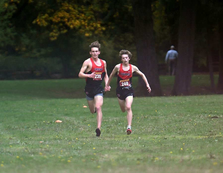 Camas juniors Hayden Reich, right, and James Puffer hold hands as they head down the stretch Wednesday, Oct. 20, 2021, during the 4A Greater St. Helens League Cross Country District Meet at Lewisville Regional Park in Battle Ground. The pair finished first and second in the race with times of 17:08.50 and 17:10.20, respectively.