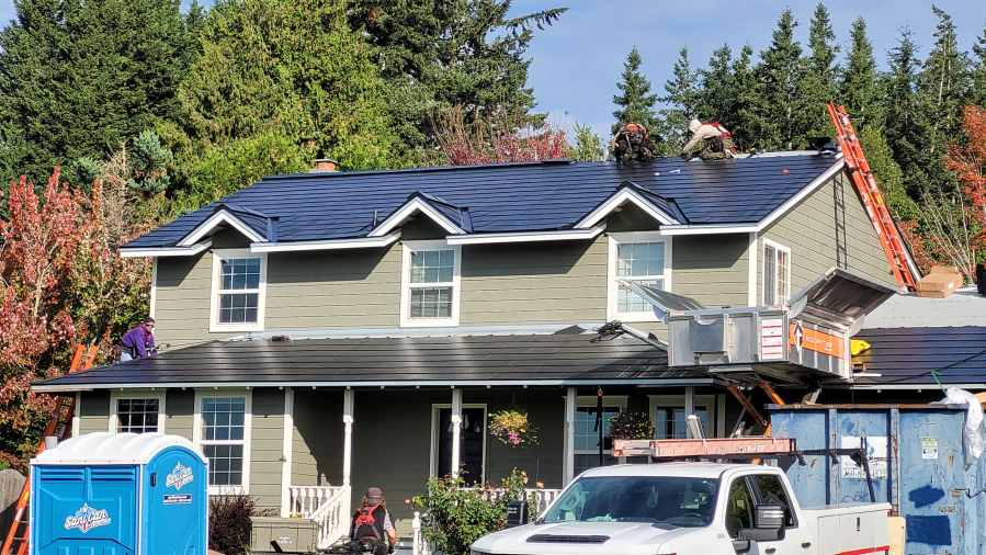Crews install a new Tesla roof at Dave Miller's Camas home. At top: The glass photovoltaic tiles in a Tesla roof are stronger than standard roofing tiles, according to the company.
