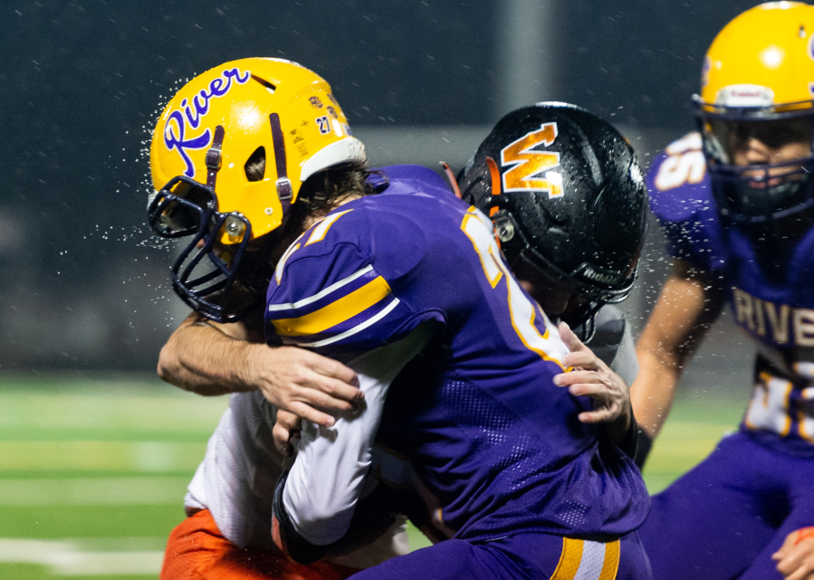 Water flies as Washougal and Columbia River players collide in a 2A Greater St. Helens League football game on Thursday, Oct. 21, at Kiggins Bowl. Columbia River won 16-13.