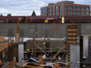 A train passes by workers as they help construct the future parking garage at the corner of Columbia Way and Esther Street in The Waterfront Vancouver on Thursday afternoon, Oct. 21, 2021.