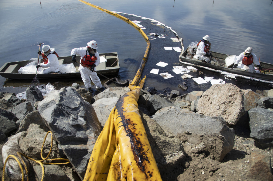 Workers with Patriot Environmental Services clean up oil that flowed into the Talbert Marsh in Huntington Beach, California on Sunday, Oct. 3, 2021. Authorities said 126,000 gallons of oil leaked from the offshore oil rig Elly on Saturday. (Myung J.