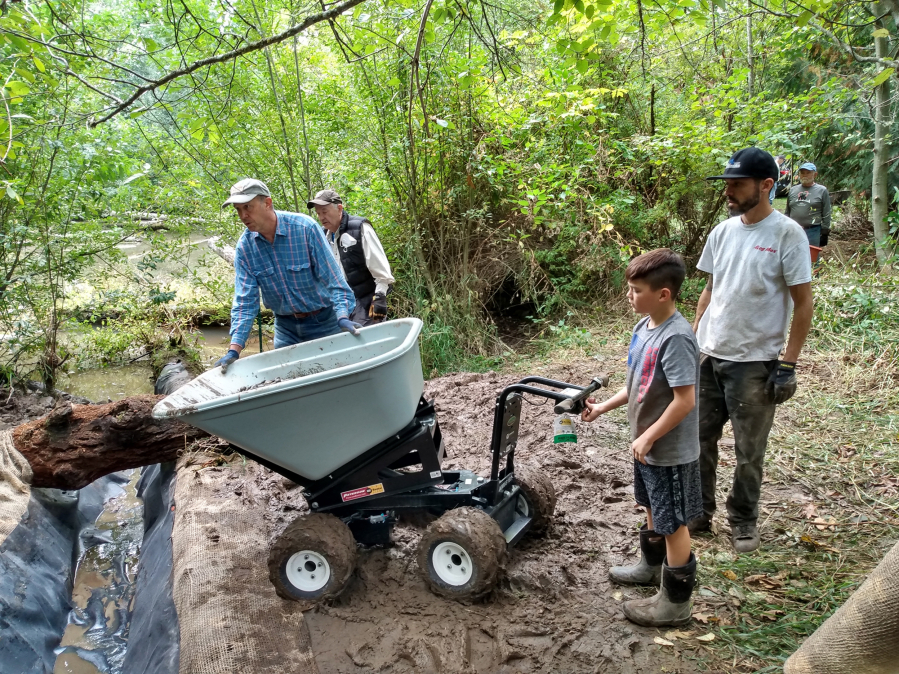 Volunteers with Trout Unlimited dig the new inflow channel to bring cold spring water into a pond in the Salmon Creek watershed. The new channel corrected a flaw in the habitat project's original design.