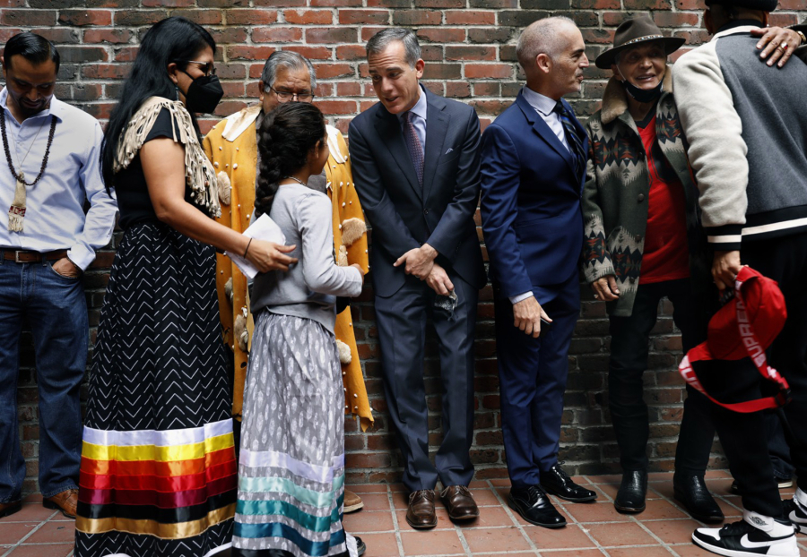 Mayor Eric Garcetti, center, mingles with members of the Gabrieleno/Tongva Tribe, left, including nine-year-old Ellie Morales Recalde, in celebration of Indigenous People's Day, during a gathering of local tribal communities along with Councilmembers Mitch O'Farrell, to the right of Mayor Garcetti, and Kevin de Leon, not pictured, who joined Mayor Eric Garcetti to announce the beginning of a process to rename La Plaza Park informally known as Father Serra Park in downtown Los Angeles on Monday, Oct. 11, 2021. An Indigenous Cultural Easement will also be created to give local indigenous communities priority access to the park for practice of traditional ceremonies.