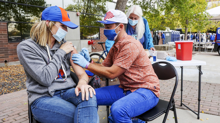 Shalyn Blaisdell, Kuna, Idaho, receives a dose of COVID-19 vaccine from Boise State nursing program student Dane Larson outside Albertsons Stadium Saturday, Sept. 18, 2021. She was attending the Broncos football game with Oklahoma State.
