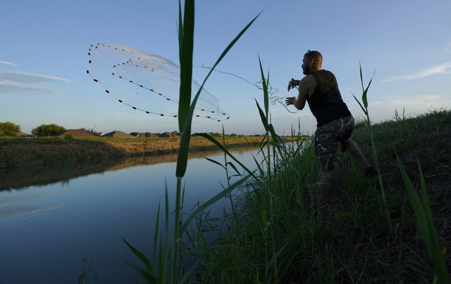 A man casts a net into a canal, Tuesday, Sept. 14, 2021, in McAllen, Texas.