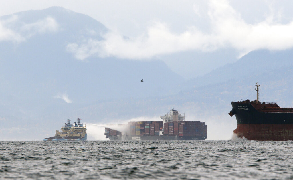 Ships work to control a fire onboard the MV Zim Kingston about eight kilometres from the shore in Victoria, B.C., on Sunday, October 24, 2021. The container ship caught fire on Saturday and 16 crew members were evacuated and brought to Ogden Point Pier.