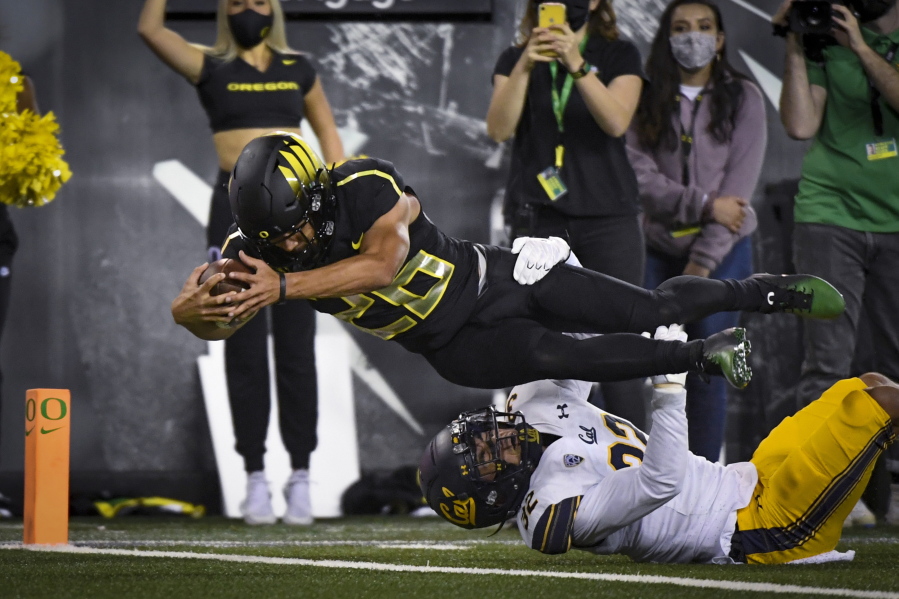 Oregon running back Travis Dye (26) dives into the end zone over California safety Daniel Scott (32) during the second quarter of an NCAA college football game Friday, Oct. 15, 2021, in Eugene, Ore.