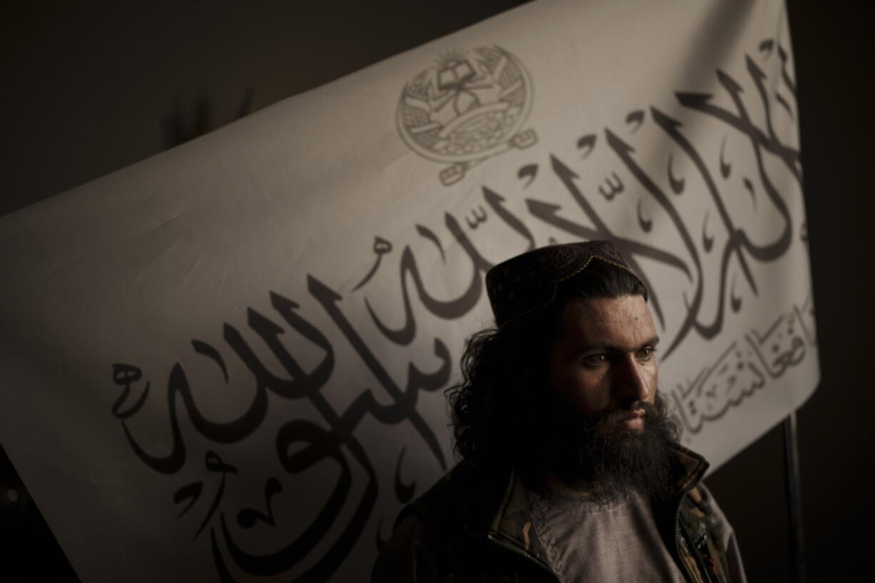 FILE - In this Sept. 20, 2021 file photo, Taliban district police chief Shirullah Badri stands in front of a Taliban flag during an interview at his office in Kabul, Afghanistan. The Islamic State in Afghanistan, emerged in 2015 when the group was at it's peak, controlling vast swathes of territory in Iraq and Syria. Now, with the U.S. exit from Afghanistan, IS is poised to usher in another violent phase - except this time it is the Taliban playing the the role of the state.
