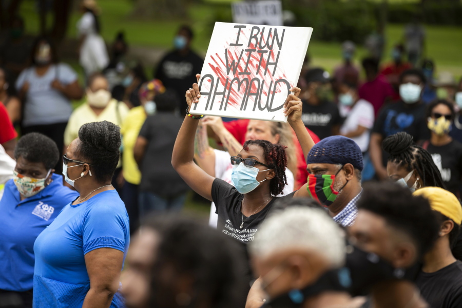 FILE - In this May 16, 2020, file photo, a woman holds a sign during a rally to protest the shooting of Ahmaud Arbery, in Brunswick, Ga. Arbery was shot and killed while running in a neighborhood outside the port city. Jury selection in the case is scheduled to begin Monday, Oct. 18. (AP Photo/Stephen B.