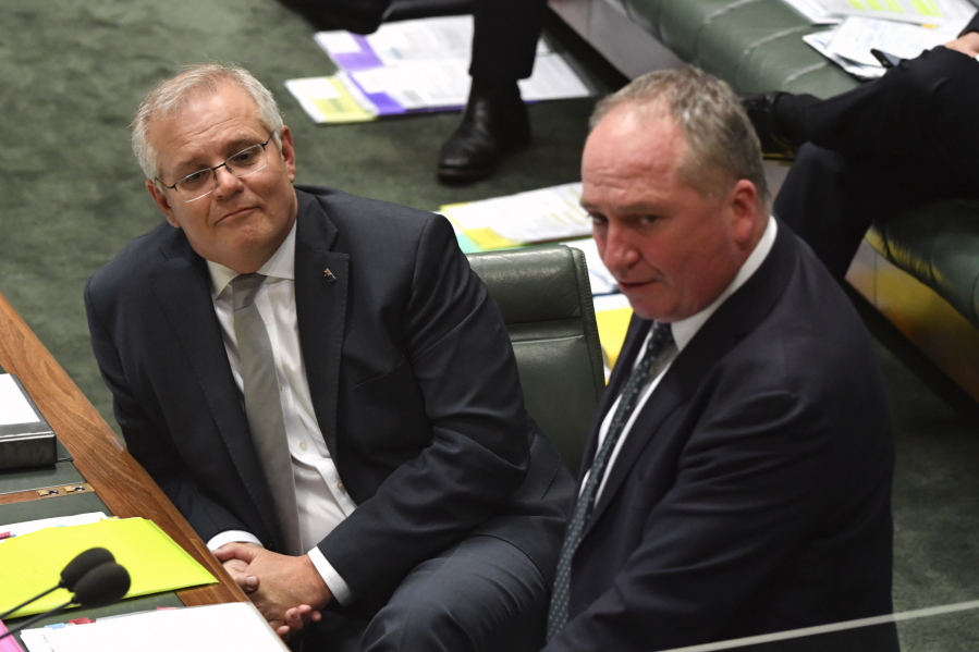 Australia's Prime Minister Scott Morrison, left, listens to Deputy Prime Minister Barnaby Joyce during question time in Parliament House in Canberra, Thursday, Oct. 21, 2021. Australia's Cabinet will on Monday, Oct. 25, 2021, consider conditions the government's junior coalition partner has placed on committing the national to a target of zero net carbon emissions by 2050.