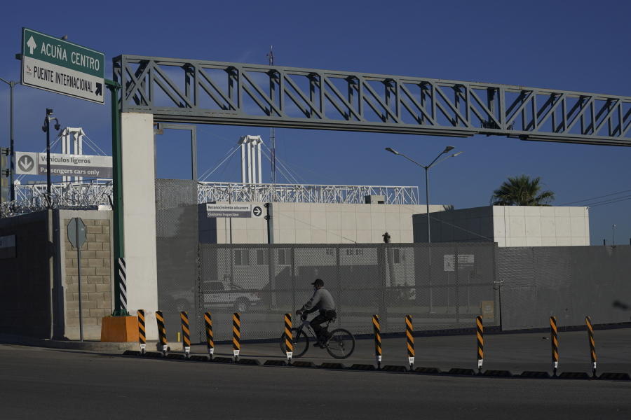 A man rides his bike past the closed main entrance of the international border bridge that connects the cities of Del Rio, Texas and Ciudad Acuna, Mexico, Friday, Sept. 24, 2021.