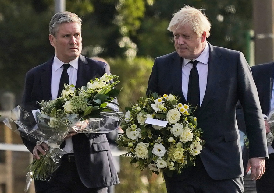 British Prime Minister Boris Johnson, right, and Leader of the Labour Party Keir Starmer carry flowers as they arrive at the scene where a member of Parliament was stabbed Friday, in Leigh-on-Sea, Essex, England, Saturday, Oct. 16, 2021. David Amess, a long-serving member of Parliament was stabbed to death during a meeting with constituents at a church in Leigh-on-Sea on Friday, in what police said was a terrorist incident. A 25-year-old man was arrested in connection with the attack, which united Britain's fractious politicians in shock and sorrow.
