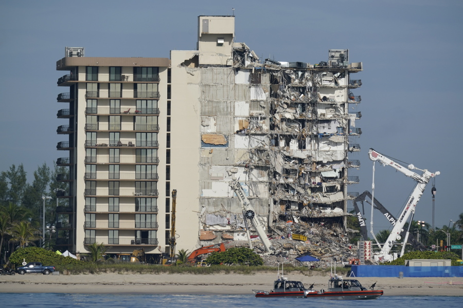 FILE - In this July 1, 2021, file photo, Coast Guard boats patrol in front of the partially collapsed Champlain Towers South condo building in Surfside, Fla. A judge pushed on Wednesday, Oct. 20, 2021, for compromise on potential payouts between people who lost loved ones and those whose units were destroyed in the deadly collapse of a Florida beachfront condominium.