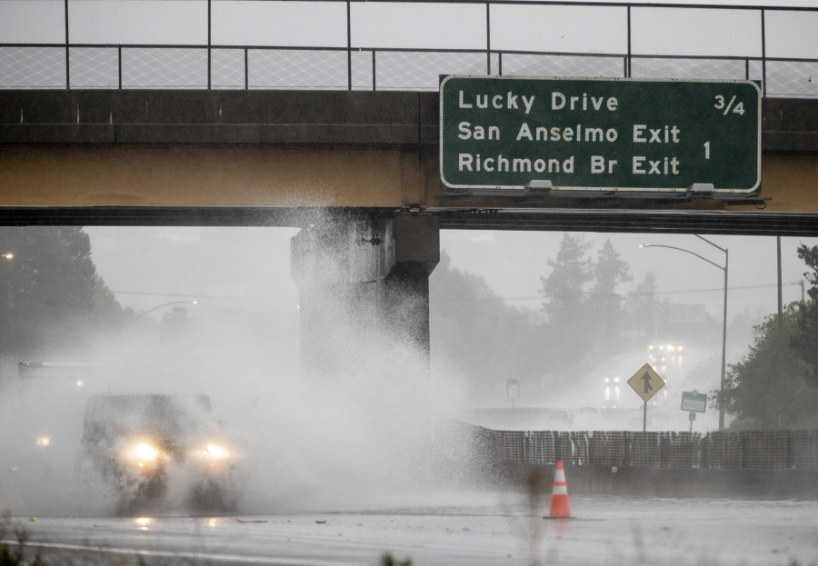 A car drives on Highway 101, which is partially flooded in Corte Madera, Calif., Sunday, Oct. 24, 2021.