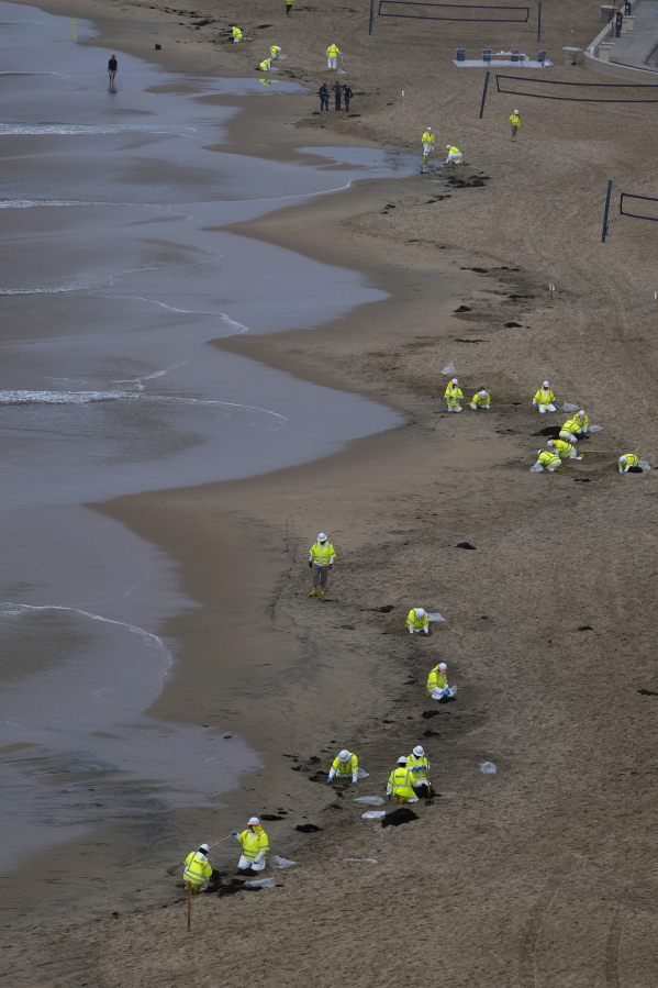 FILE - Workers in protective suits clean the contaminated beach in Corona Del Mar after an oil spill in Newport Beach, Calif., on Thursday, Oct. 7, 2021. After a crude oil sheen was detected on the waters off the California coast, environmentalists feared the worst. Now, almost a week later, some say weather conditions and quick-moving actions have spared sensitive wetlands and scenic beaches in Orange County's Huntington Beach a potentially calamitous fate, though the long term toll of the spill remains unknown. (AP Photo/Ringo H.W.