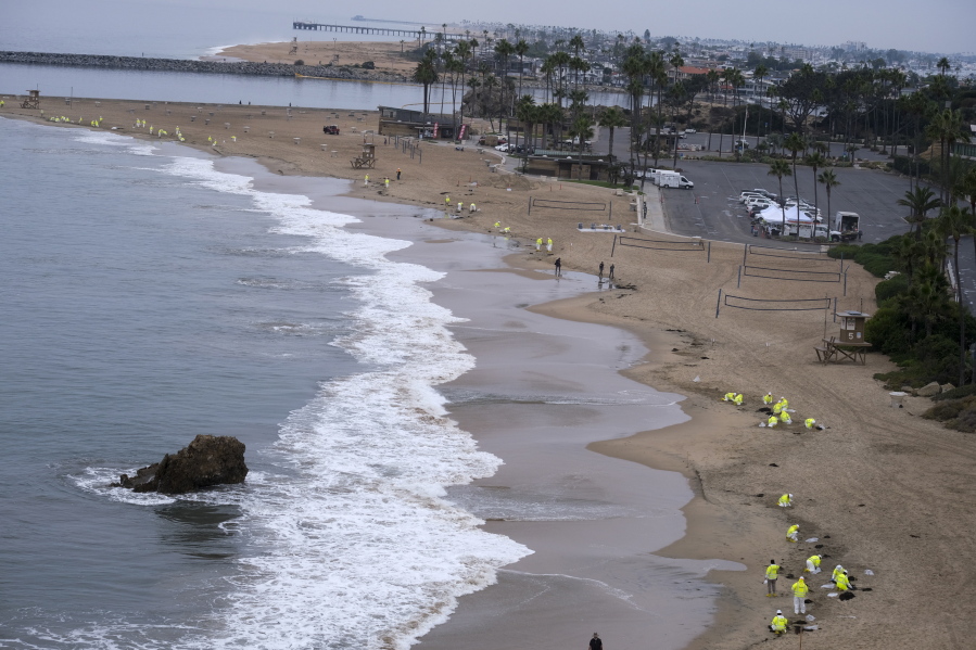 FILE - In this Thursday, Oct 7, 2021 file photo, Workers in protective suits clean the contaminated beach in Corona Del Mar after an oil spill in Newport Beach, Calif. California's uneasy relationship with the oil industry is being tested again by the latest spill to foul beaches and kill birds and fish off Orange County. (AP Photo/Ringo H.W.