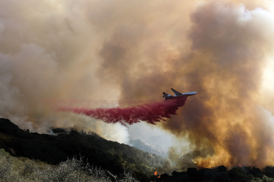 FILE - In this Oct. 13, 2021, file photo, an air tanker drops retardant on a wildfire in Goleta, Calif. Firefighters persisted in making progress Saturday, Oct. 17, against a wildfire burning for a sixth day in Southern California coastal mountains. The Alisal Fire in the Santa Ynez Mountains west of Santa Barbara grew only slightly since Friday to nearly 27 square miles (69 square kilometers). It was 50% contained. (AP Photo/Ringo H.W.