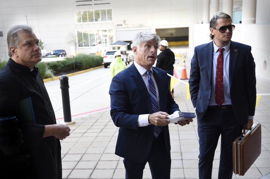 FILE - Fr. Paul Kalchik, left, St. Michael's Media founder and CEO Michael Voris, center, and Milo Yiannopoulos talk with a court officer before entering the federal courthouse, Sept. 30, 2021 in Baltimore. A federal judge has blocked Baltimore city officials from banning the conservative Roman Catholic media outlet from holding a prayer rally at a city-owned pavilion during a U.S. bishops' meeting next month. U.S. District Judge Ellen Hollander ruled late Tuesday, Oct. 13, 2021 that St. Michael's Media is likely to succeed on its claims that the city discriminated against it on the basis of its political views and violated its First Amendment free speech rights.