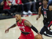 Portland Trail Blazers guard Damian Lillard, left, drives to the basket in front of Los Angeles Clippers guard Terance Mann during the first half of an NBA basketball game in Portland, Ore., Friday, Oct. 29, 2021.