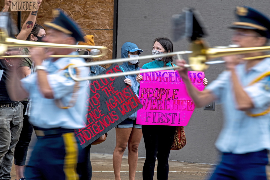 A band passes protesters as they stand Saturday route of the Pittsburgh Columbus Day Parade in Pittsburgh. Communities across the U.S. are taking a deeper look at Columbus' legacy in recent years.