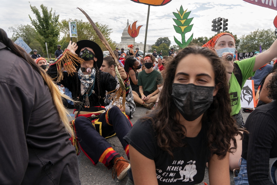 Ira Francisco, 21, of Chicago, left, who is Navajo and Ojibwe, joins a chant during an act of civil disobedience by the U.S. Capitol, Friday, Oct. 15, 2021, during a climate change protest including indigenous and youth activists, in Washington. "I stand with my people," says Francisco, "this is our land.