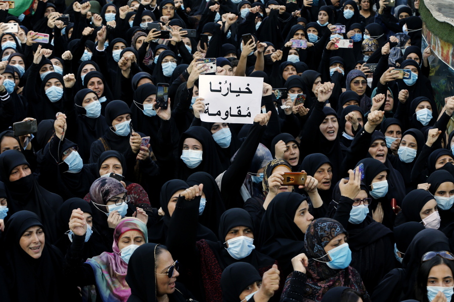 FILE - In this Oct. 15, 2021, mourners chant slogans as they hold a placard with Arabic that reads "Our choice is resistance" during the funeral of three Hezbollah supporters who were killed during clashes, in the southern Beirut suburb of Dahiyeh, Lebanon. Internal company documents from the former Facebook product manager-turned-whistleblower Frances Haugen show that in some of the world's most volatile regions, terrorist content and hate speech proliferate because the company remains short on moderators who speak local languages and understand cultural contexts.