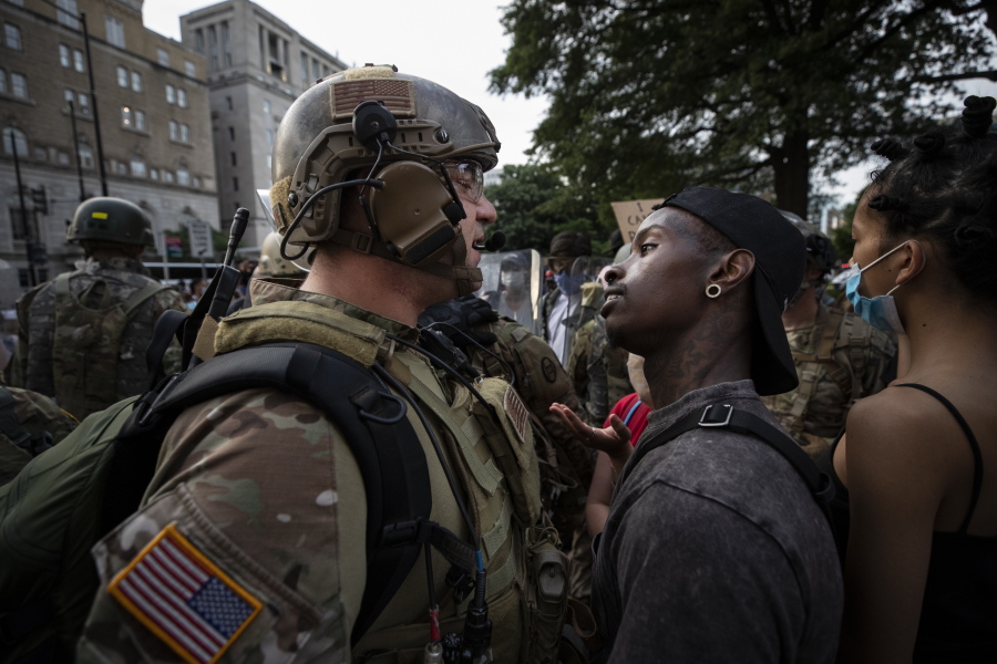 FILE - In this June 3, 2020, file photo, a demonstrator stares at a National Guard soldier as protests continue over the death of George Floyd, near the White House in Washington, D.C. Reports of hateful and violent speech on Facebook poured in on the night of May 28 after President Donald Trump hit send on a social media post warning that looters who joined protests following Floyd's death last year would be shot, according to internal Facebook documents shared with The Associated Press.