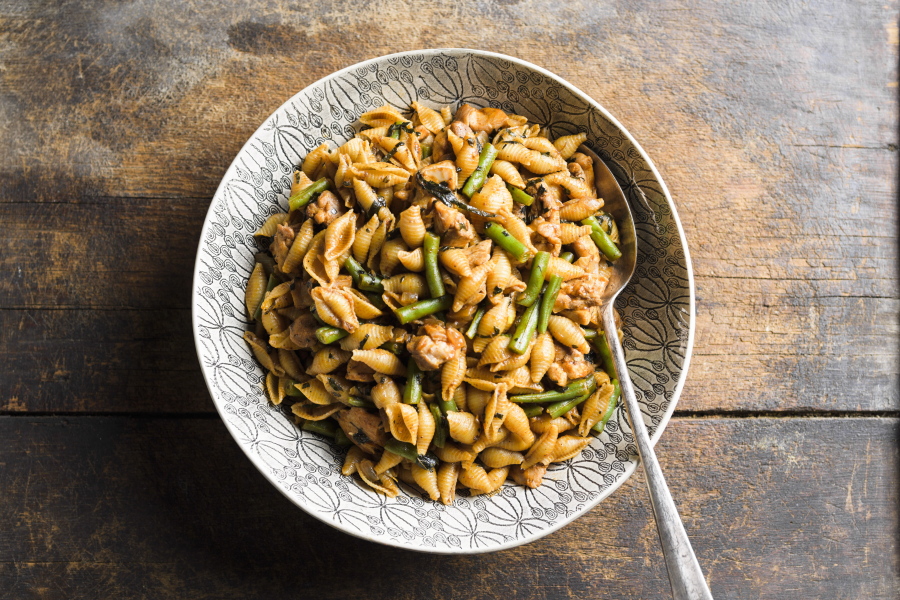 This image released by Milk Street shows a recipe for harissa-spiced pasta with chicken and green beans.