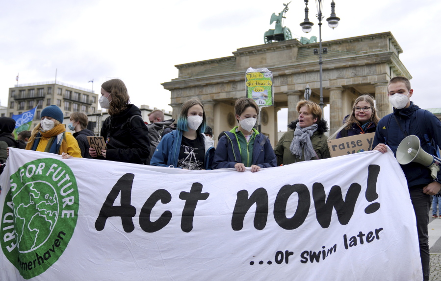 People stay in front of the Brandenburg Gate as they take part in a 'Fridays For Future' climate protest rally in Berlin, Germany, Friday, Oct. 22, 2021.