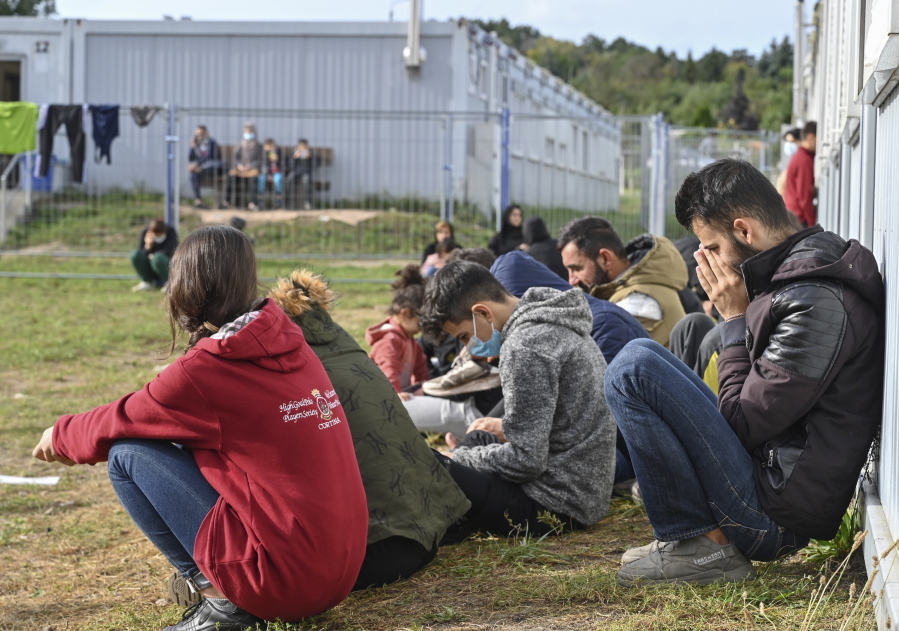 Migrants sit in front of containers at the Central Initial Reception Facility for Asylum Seekers, ZABH, in the federal German state of Brandenburg in Eisenhuettenstadt, Germany, Wednesday, Oct. 6, 2021. German federal police said more than 4,300 people crossed the border from Poland 'illegally' this year. Most people are being put up at asylum centers in the eastern state of Brandenburg.
