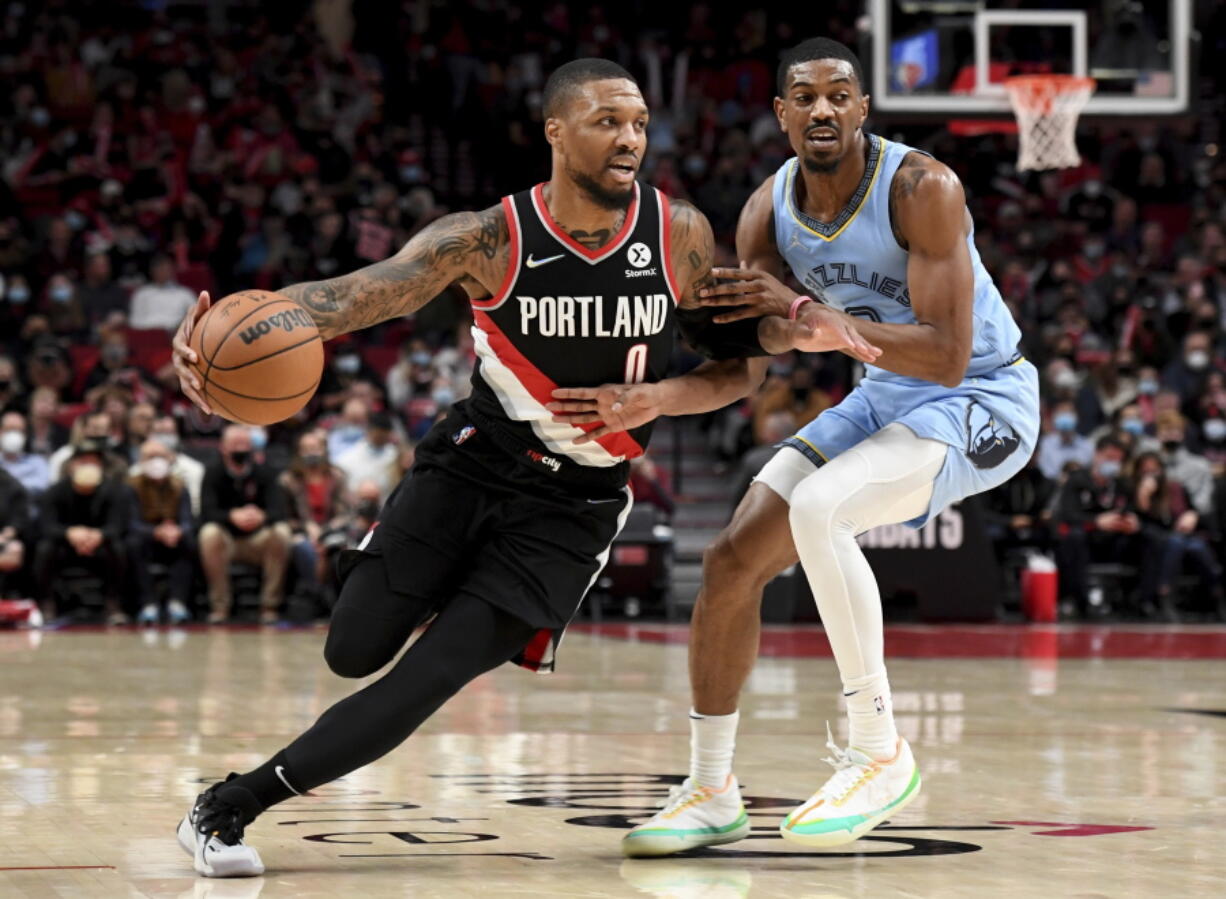 Portland Trail Blazers guard Damian Lillard, left, drives to the basket on Memphis Grizzlies guard De'Anthony Melton, right, during the first half of an NBA basketball game in Portland, Ore., Wednesday, Oct. 27, 2021.
